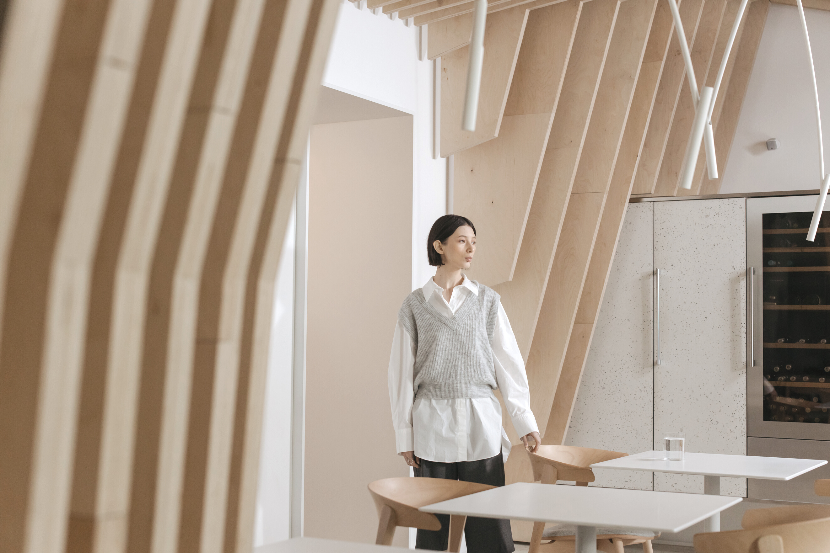 Woman Standing by Desks in Wood Covered Room